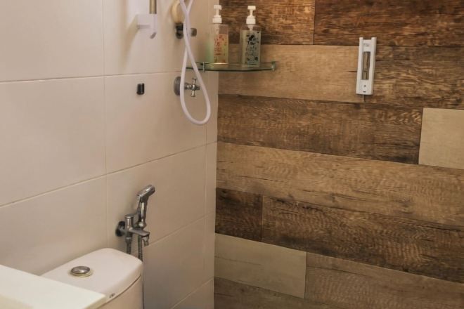 A bathroom with a shower, toilet, and a shelf with toiletries.