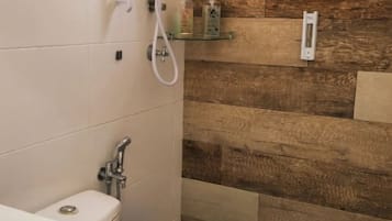 A bathroom with a shower, toilet, and a shelf with toiletries.