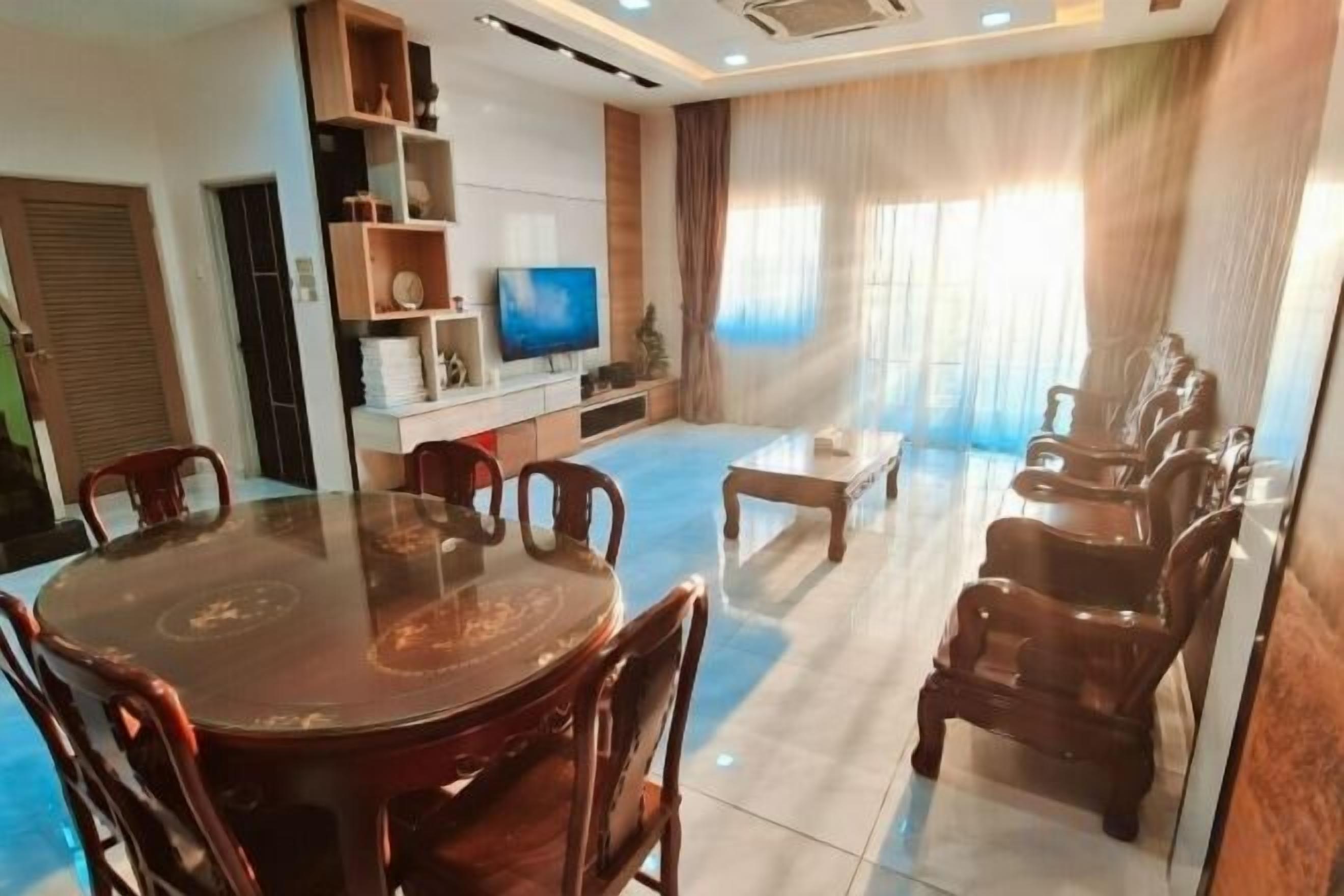 A dining area with a round table and chairs, a television, and a seating area with sofas.