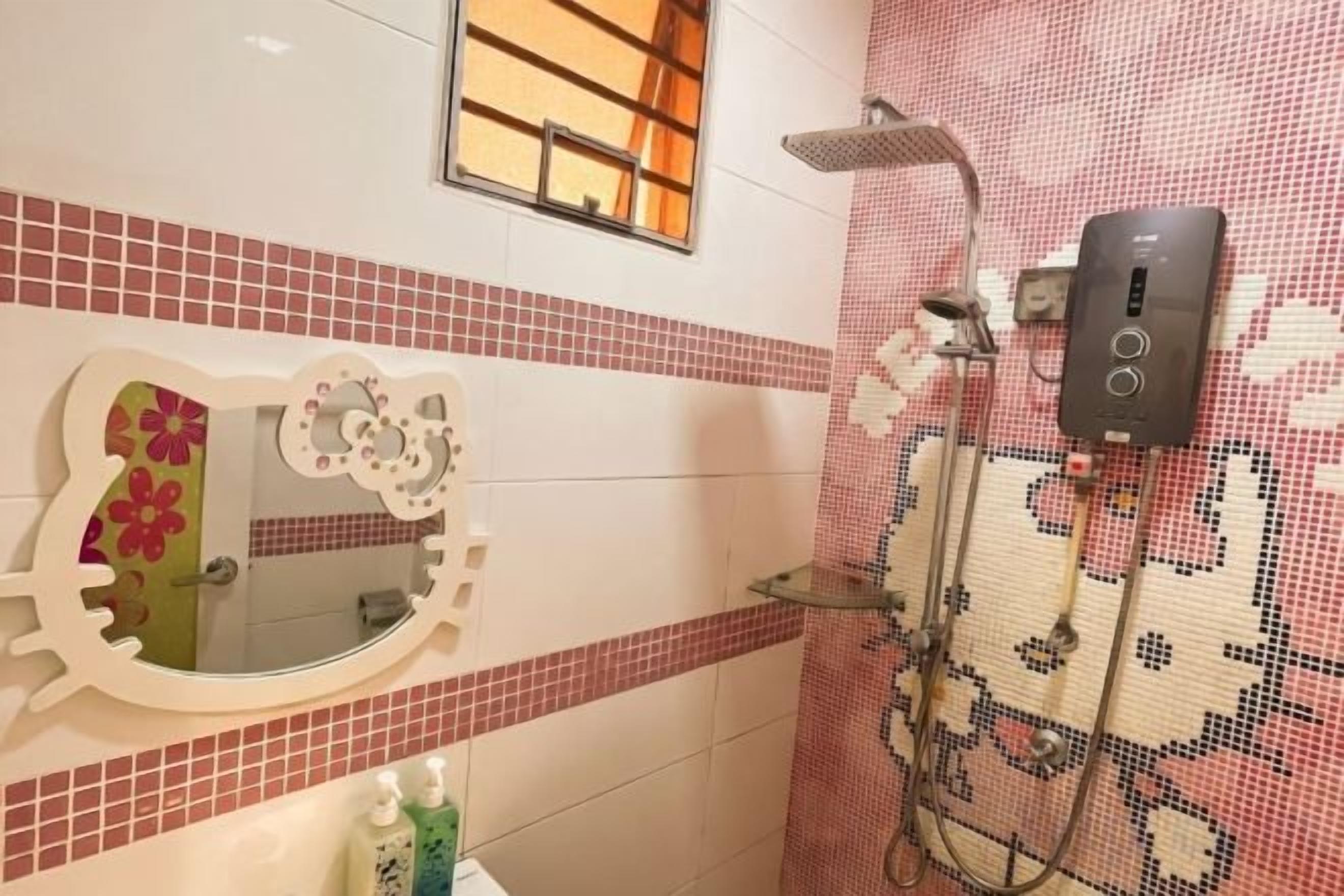 A bathroom with a mirror, tiled walls, a shower, and a control panel.