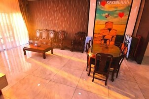 Un vestíbulo con piso pulido, una mesa redonda con sillas y una pared con diseño.