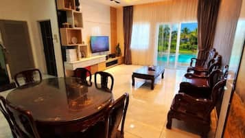 A modern living room with a dining table, chairs, a sofa, and a TV.