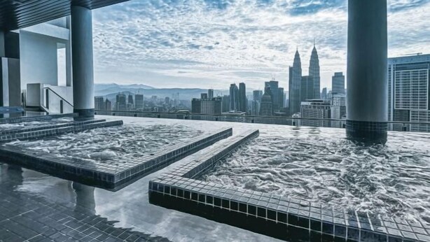Piscina no terraço com vista para a paisagem urbana, incluindo um arranha-céu imponente.