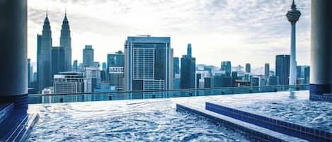 A rooftop pool with a city skyline view, including prominent buildings and a tower.