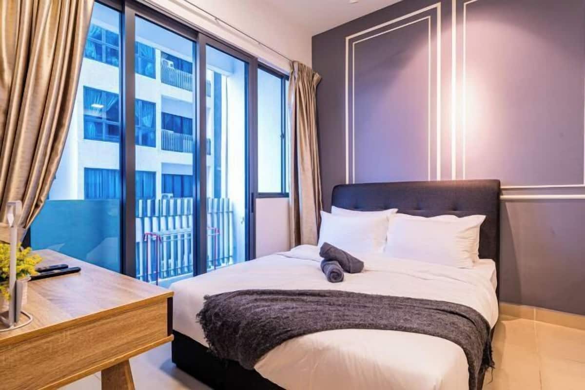 Een hotelkamer met een groot bed, een bureau met een lamp en uitzicht op een gebouw.