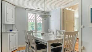Een eethoek met een witte tafel en stoelen, een plafondventilator en een raam met gestreepte gordijnen.
