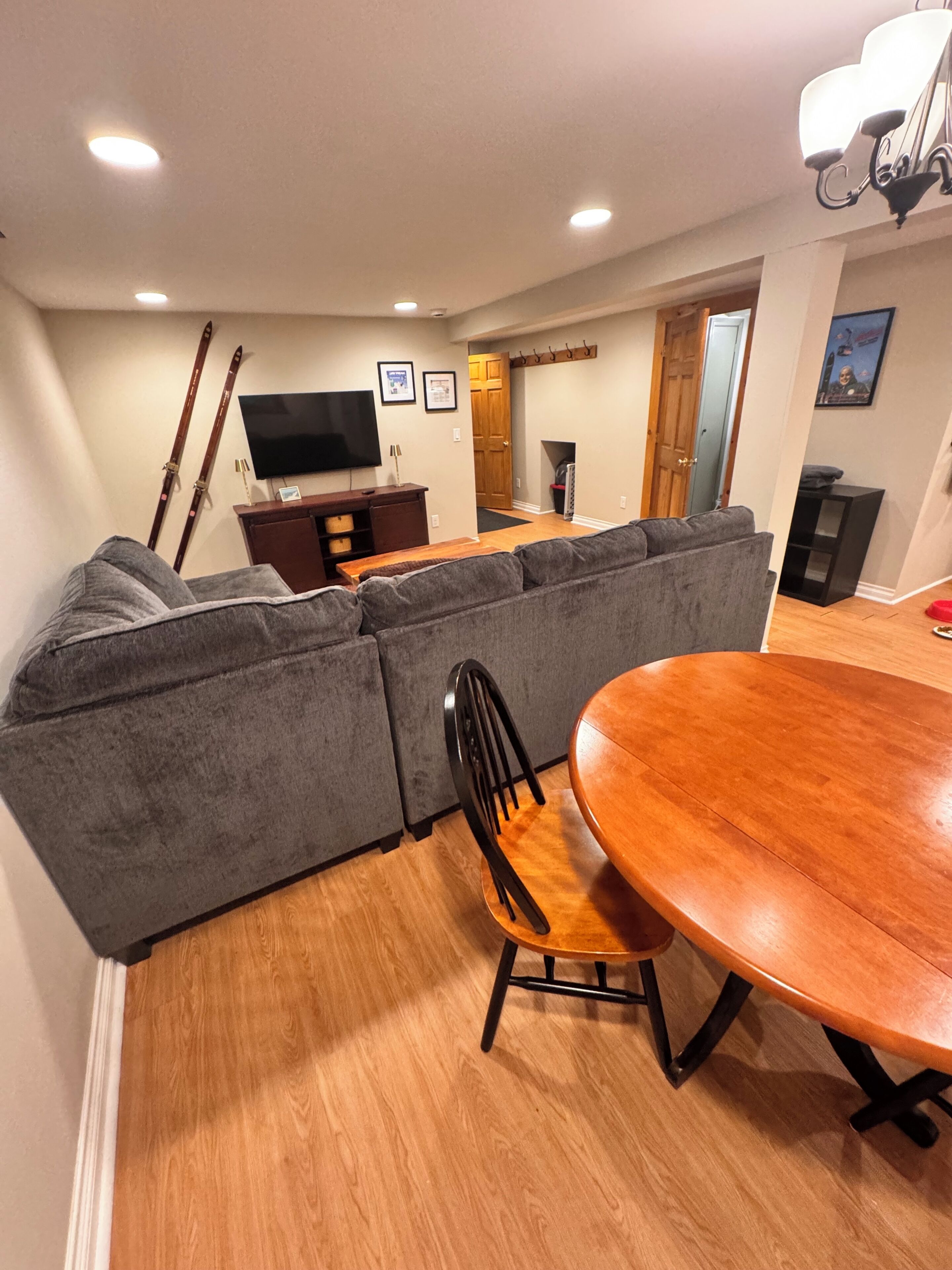 Una sala de estar con un sofá modular, una mesa de comedor de madera con sillas, un televisor y una chimenea.