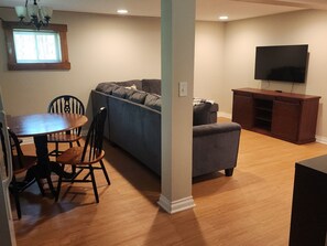 A living room with a dining table, chairs, a sofa, a TV, and a wooden cabinet.