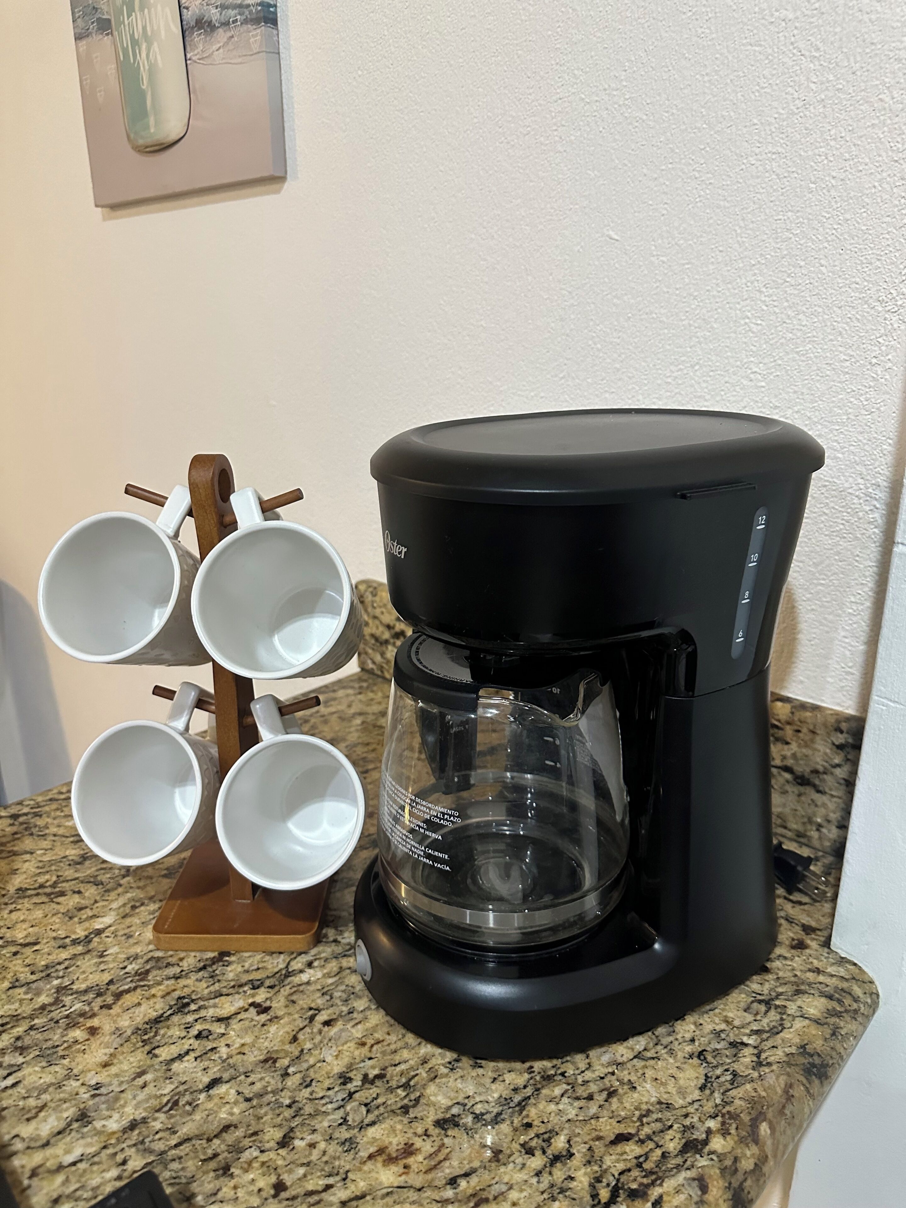 A coffee maker on a granite countertop with a mug holder to the left.