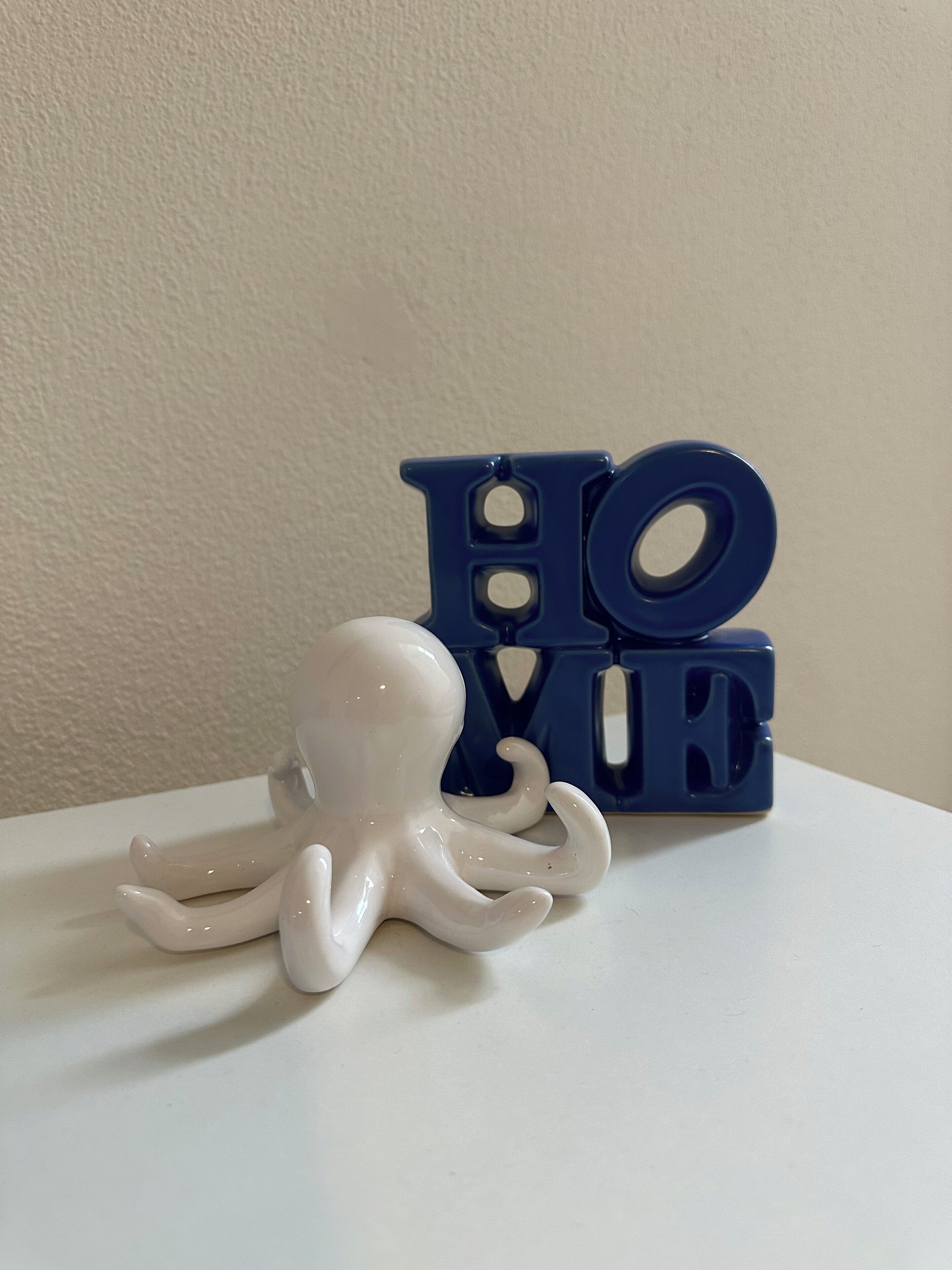 Eine weiße Tintenfischfigur neben blauen Buchstaben, die „HOPE“ schreiben.