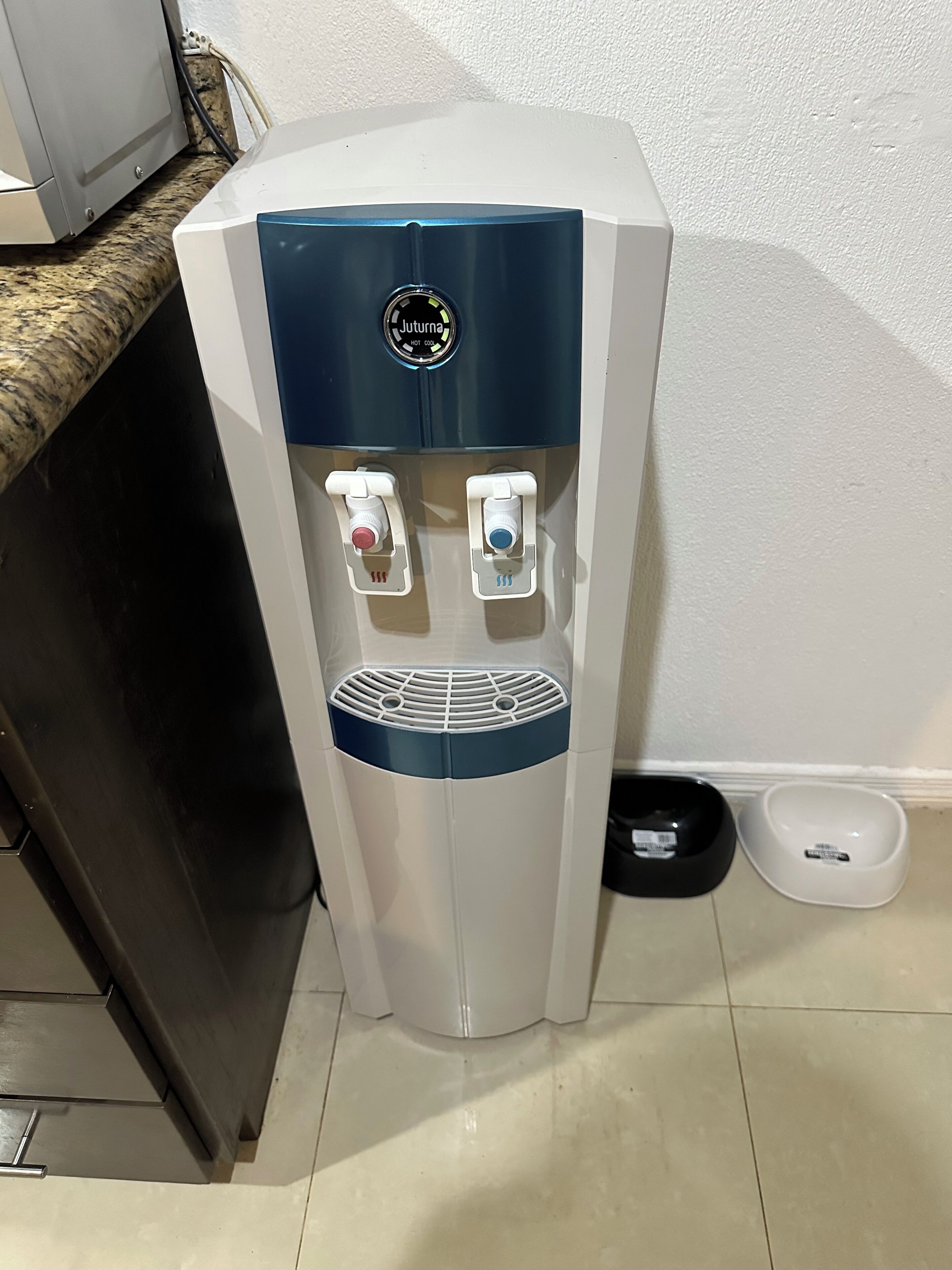 Um dispensador de água com dois bicos, um para água quente e outro para água fria, e um painel de controle com o logotipo da marca.
