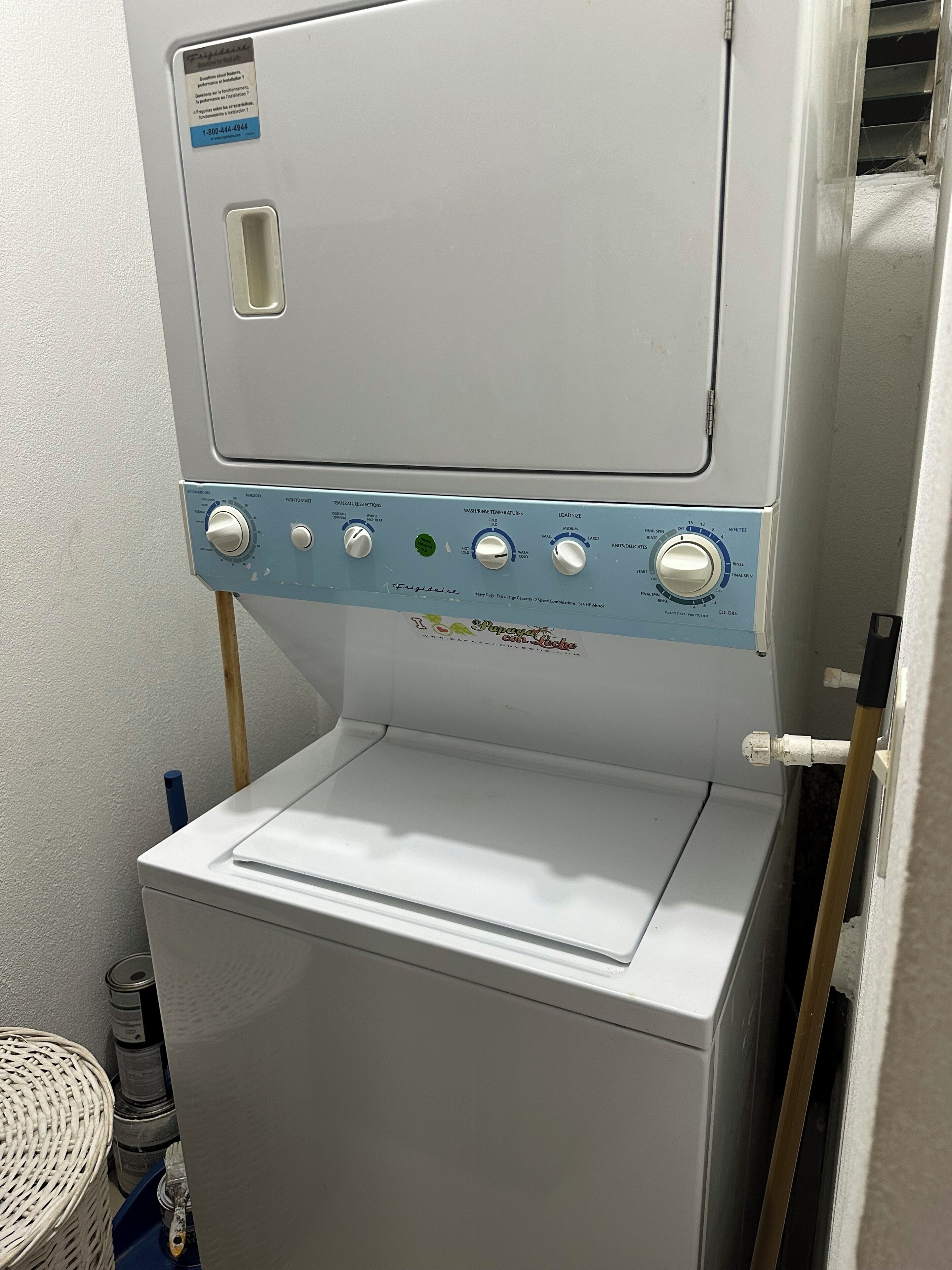 Una lavadora de carga frontal con panel de control, una cesta y un secadora de pared.
