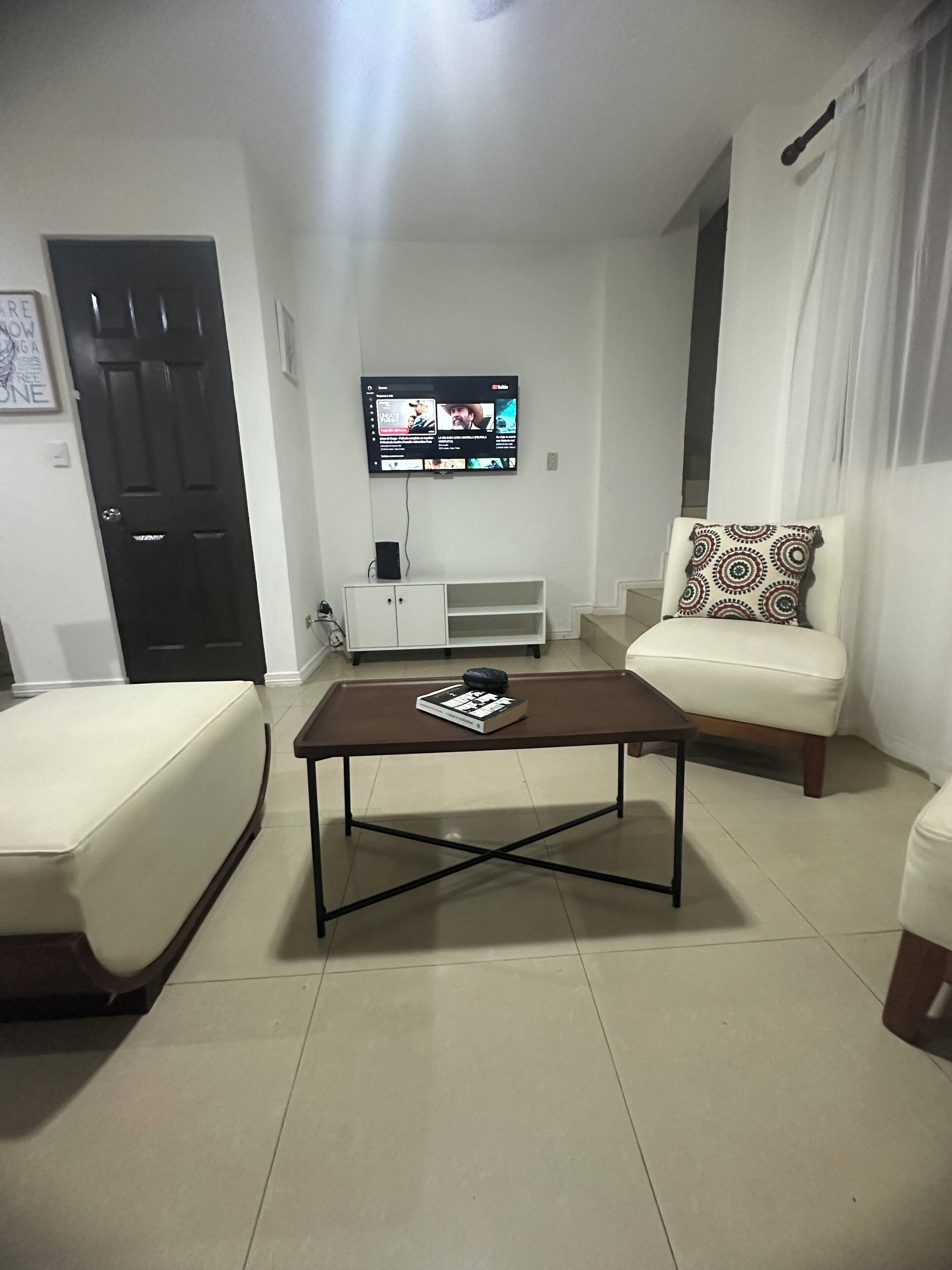 Un salon avec un téléviseur fixé au mur, un canapé, une table basse et un meuble.