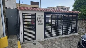 Uma entrada protegida por portão de metal e um pequeno edifício com telhado em azulejos.