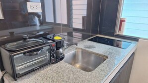Uma cozinha com forno embutido, cafeteira e pia de aço inoxidável.