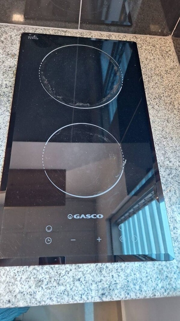 A black induction cooktop with two control knobs and a brand name 'GASCO' on a granite countertop. - Charming modern studio! (Ciudad de panama)