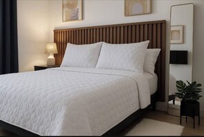 A neatly made bed with a wooden headboard, a bedside lamp, and a large mirror on the wall. - Charming modern studio! (Ciudad de panama)