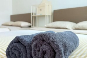 A neatly made bed with a rolled towel, a crib, and pillows in a hotel room. - Golden Sweet Home @ CH Golden Hills (Night Market) - 2 Storey Terrace House (Brinchang)