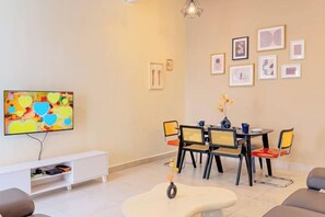 A living room with a television, a dining table with chairs, a sofa, and artwork on the wall. - Golden Sweet Home @ CH Golden Hills (Night Market) - 2 Storey Terrace House (Brinchang)