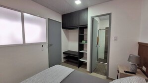 Una camera da letto con un letto, un armadio, uno specchio e un comodino con una lampada.