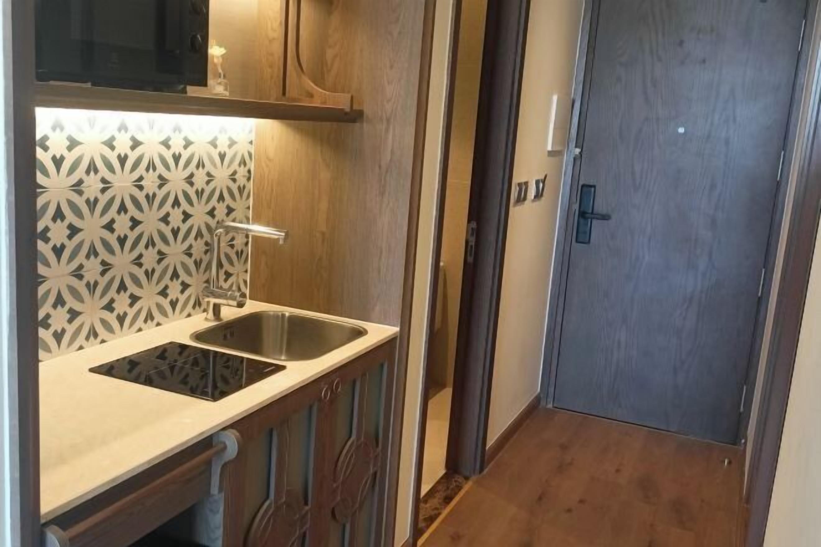 Una cocina compacta con un lavamanos doble, armarios de madera y un salpicadero con estampado.