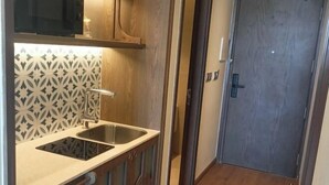 Une cuisine compacte dotée d’un évier à deux bacs, de meubles en bois et d’un crédence à motifs.