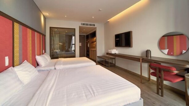 Une chambre d’hôtel avec deux lits, un bureau, une chaise, une télévision et un miroir.
