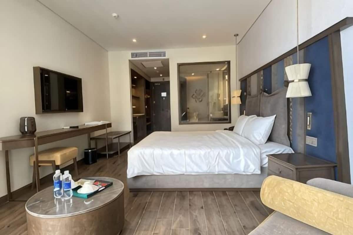 Une chambre d’hôtel comprenant un lit, un bureau, une chaise, une petite table ronde et un téléviseur.