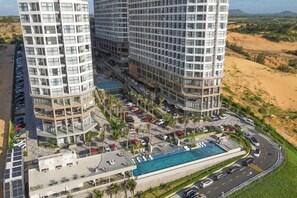 A high-rise hotel with multiple floors, a swimming pool, and a parking area.