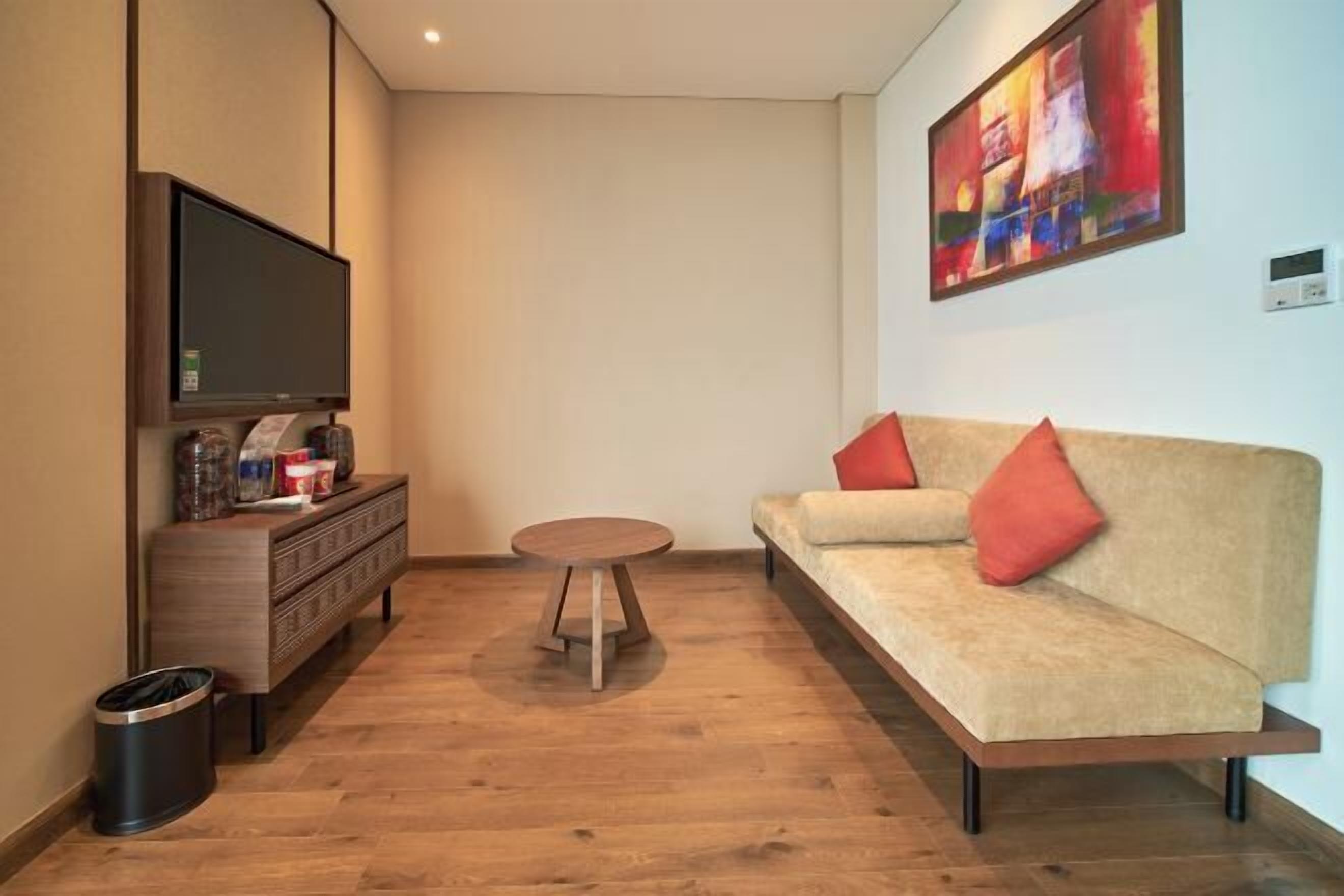 Una sala de estar moderna con un sofá, una mesa de centro y un televisor sobre un mueble de madera.