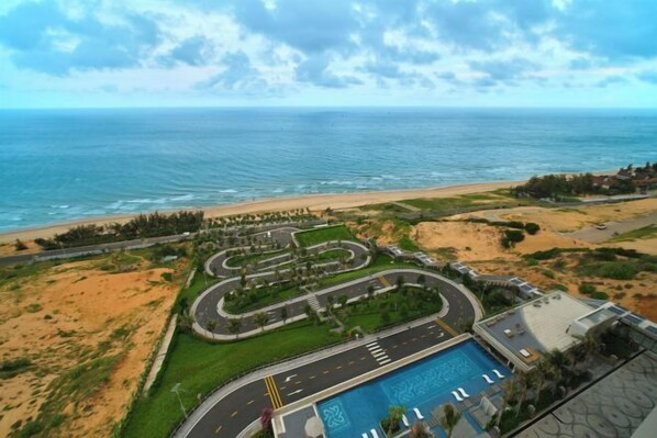 Un complejo turístico costero con una carretera sinuosa, una piscina y vistas a la playa.