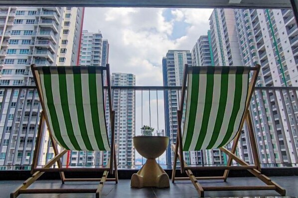 Two green and white striped lounge chairs facing a balcony with a view of high-rise buildings.