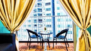 A balcony with two chairs and a small table, overlooking a high-rise building.