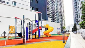 A playground with slides and climbing structures, surrounded by tall residential buildings.