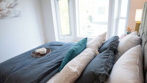A neatly made bed with a variety of pillows and a tray with a book and a cup. - Central 3BR Getaway/ Family-sized, Free Parking & AC/ Near Downtown (Edmonton)