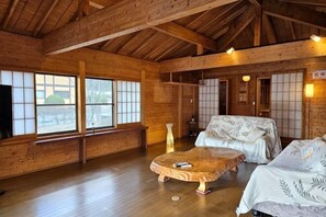 Interior de madera con esteras de tatami, una mesa baja de madera y puertas correderas tradicionales japonesas.