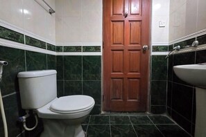 A bathroom with a toilet, a sink, and a wooden door. - Hotel O Kota Bharu Near War Museum Formerly Azam Hotel (Kota Bharu)