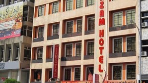 Un immeuble à plusieurs étages, sur lequel on peut voir une enseigne bien visible pour l’hôtel Azam.