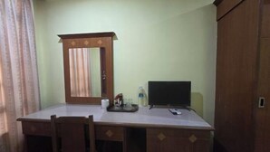 Une pièce comprenant un bureau, une chaise, un miroir, une télévision et une armoire.