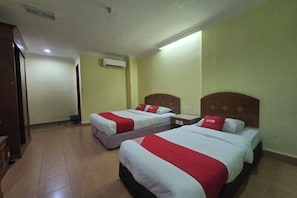 A hotel room with two beds, each with red and white bedding, a wooden headboard, and an air conditioning unit on the wall. - Hotel O Kota Bharu Near War Museum Formerly Azam Hotel (Kota Bharu)