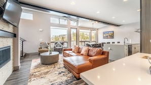 A modern living room with a leather sofa, a round coffee table, and a large window offering a view of the outdoors.