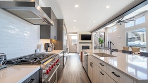 A modern kitchen with stainless steel appliances, a central island, and a large window providing natural light.