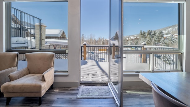 A modern interior with large windows, a plush armchair, and a view of a snowy landscape.