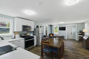 A modern kitchen with white cabinets, stainless steel appliances, and a dining area with wooden chairs and a table.