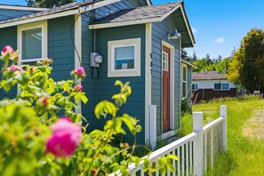 A house with a white picket fence, a green exterior, and a red door.