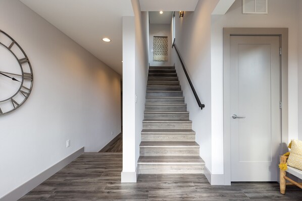 A staircase with a wooden finish, a white door, and a wall-mounted clock.