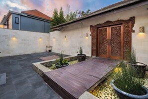 Une cour avec une terrasse en bois, des plantes en pot et un mur décoratif.