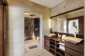 Une salle de bain avec deux lavabos, un grand miroir et un espace douche.
