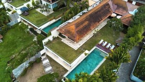Une maison moderne dotée d’une grande piscine, d’un patio couvert et d’une pelouse bien entretenue.