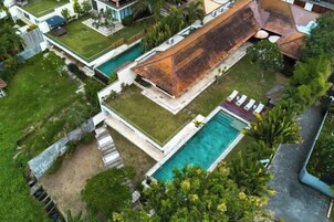 Una casa moderna con una gran piscina, un porche cubierto y un césped bien cuidado.
